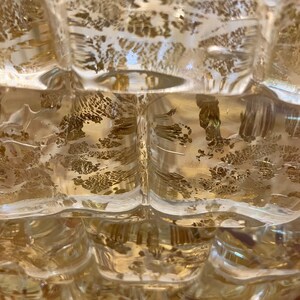 May include: A clear glass vase with a textured surface and gold flecks throughout. The vase has a rounded shape with a wide opening at the top.