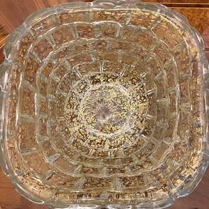 May include: A clear glass bowl with a textured surface and gold flecks throughout. The bowl has a rounded, slightly wavy rim.