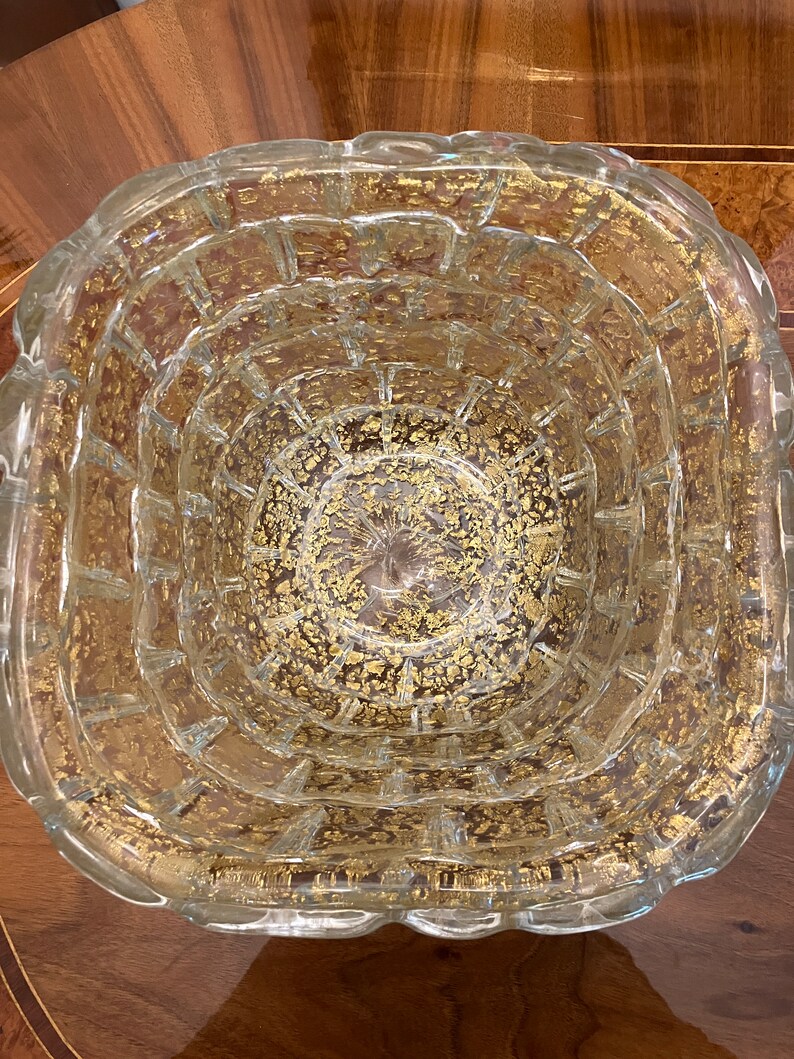 May include: A clear glass bowl with a textured surface and gold flecks throughout. The bowl has a rounded, slightly wavy rim.