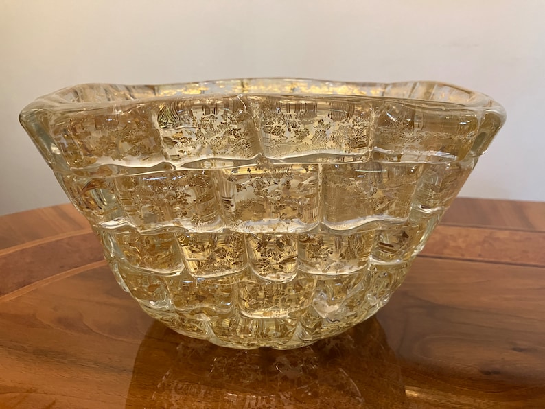 May include: A clear glass bowl with a textured, woven design. The bowl has a gold-like sheen and is perfect for serving snacks or holding decorative items.