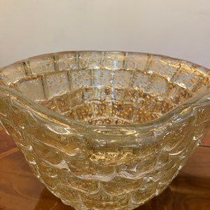 May include: A clear glass bowl with a textured, woven design and gold flecks throughout. The bowl has a rounded shape and a wide rim.