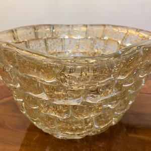 May include: A clear glass bowl with a textured, woven design. The bowl has a gold metallic finish and is perfect for serving snacks or fruit.