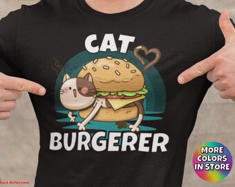 May include: A black t-shirt with a white graphic of a cat wearing a hamburger as a hat. The text "Cat Burgerer" is printed below the graphic.
