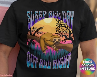 Könnte beinhalten: Schwarzes T-Shirt mit einer bunten Grafik eines schlafenden Faultiers auf einem Ast mit dem Text "Sleep All Day Out All Night".