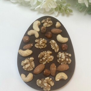 May include: A dark chocolate egg-shaped candy bar with a variety of nuts, including almonds, cashews, and walnuts.