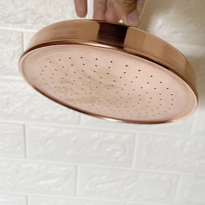 May include: A copper shower head with a round shape and a large number of small holes for water to flow through.