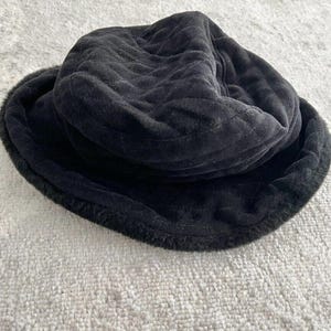 Könnte beinhalten: Ein schwarzer gesteppter Bucket-Hut mit Kunstfellbesatz.