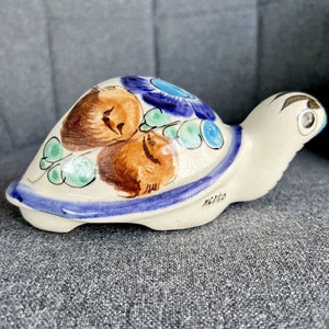 May include: A hand-painted ceramic turtle figurine with blue, green and brown floral designs. The turtle is made in Mexico and has a white base.