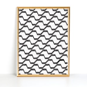 May include: A framed art print featuring a black and white geometric pattern. The design consists of repeating, interconnected zigzag lines with a mosaic-like texture. The artwork is encased in a gold-colored frame, adding a touch of elegance.