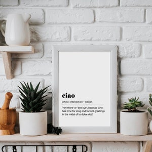 May include: A white framed print with the word "ciao" in bold black text. The definition of the word is written in smaller black text below. The definition reads: "[chow] interjection - Italian "hey there" or "bye bye", because who has time for long and formal greetings in the midst of la dolce vita?"