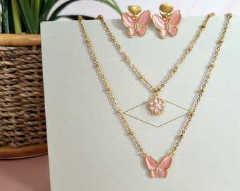May include: A gold layered necklace with a pink butterfly pendant and a cluster of pink stones. Matching pink butterfly earrings are also included.