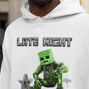 Könnte beinhalten: Weißer Hoodie mit einem grünen Minecraft Creeper-Charakter, der eine goldene Kette und einen grauen Stern trägt. Der Text "Late Night Creeperstar" ist auf dem Hoodie aufgedruckt.