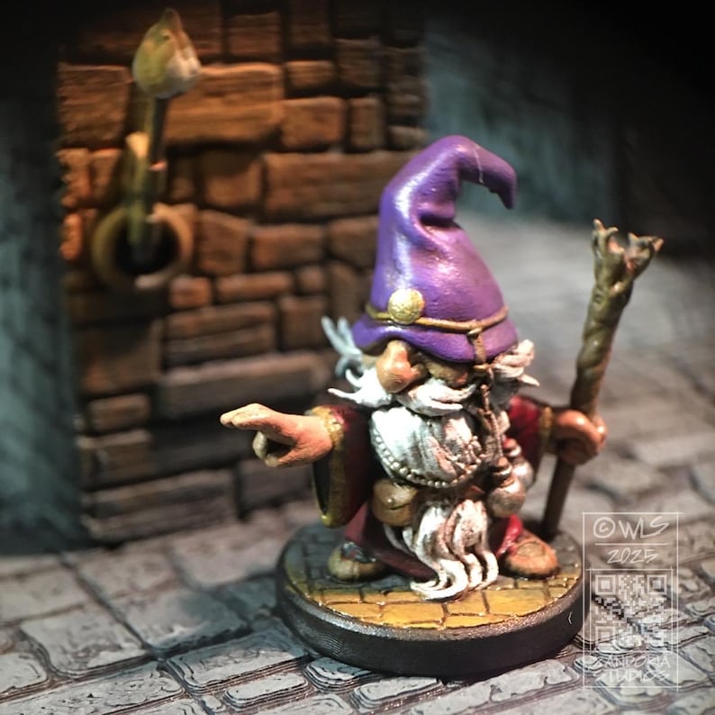 Pu&ograve; includere: Una figurina miniatura dipinta di un mago con un cappello viola e una barba bianca, che tiene uno scettro. Il mago sta puntando con la mano destra e sta in piedi su una base rotonda con un design giallo e marrone. La miniatura fa parte di un gioco da tavolo.