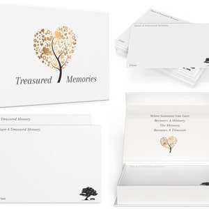 May include: A white box with a gold heart-shaped tree design and the text "Treasured Memories". The box contains a stack of white note cards with the text "Share A Treasured Memory" and a black tree design.