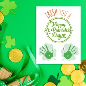 May include: A white card with green shamrocks and the text "Irish You A Happy St. Patrick's Day" in green lettering. The card is surrounded by green shamrocks, gold coins, and green ribbon.