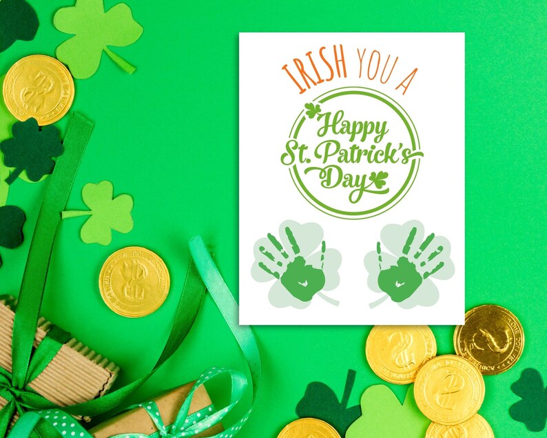May include: A white card with green shamrocks and the text "Irish You A Happy St. Patrick's Day" in green lettering. The card is surrounded by green shamrocks, gold coins, and green ribbon.
