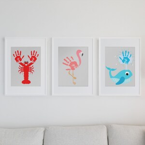 May include: Three framed handprint art pieces depicting a lobster, flamingo, and whale. The lobster is red, the flamingo is pink, and the whale is blue.