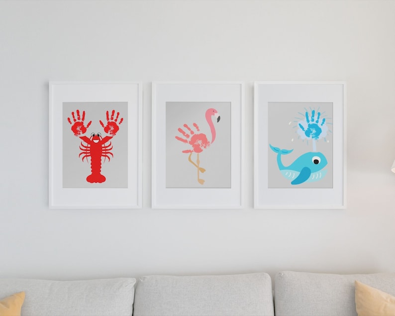 May include: Three framed handprint art pieces depicting a lobster, flamingo, and whale. The lobster is red, the flamingo is pink, and the whale is blue.