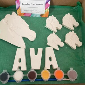 May include: A craft kit for painting a horse head and the name AVA. The kit includes four white ceramic horse heads, three white ceramic letters spelling AVA, six paint pots, and a paintbrush.