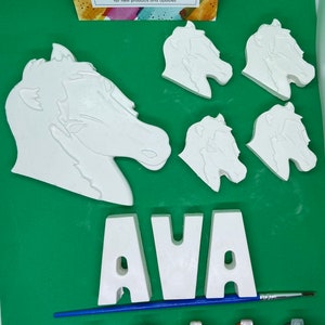 May include: A craft kit for painting a horse head and the name AVA. The kit includes five white ceramic pieces, six paint pots, and a paintbrush. The paint pots are black, white, brown, yellow, orange, and brown.