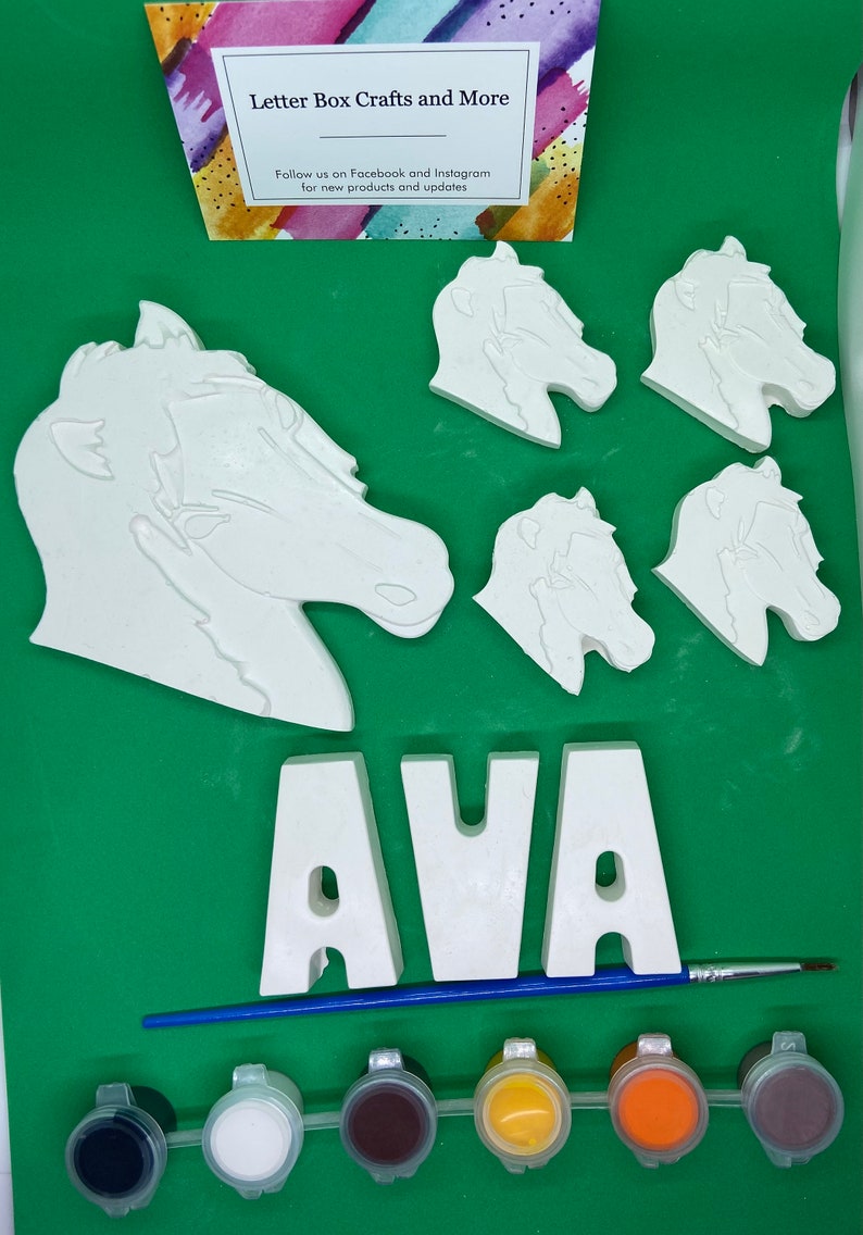 May include: A craft kit for painting a horse head and the name AVA. The kit includes five white ceramic pieces, six paint pots, and a paintbrush. The paint pots are black, white, brown, yellow, orange, and brown.