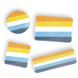 May include: Four different sized buttons with the colors of the genderqueer pride flag. The flag has stripes of orange, yellow, white, light blue, and dark blue.