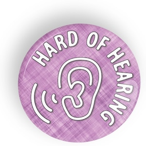 Puede incluir: Botón morado con un contorno blanco de una oreja y ondas sonoras. El texto "HARD OF HEARING" está escrito alrededor de la oreja en un contorno blanco.