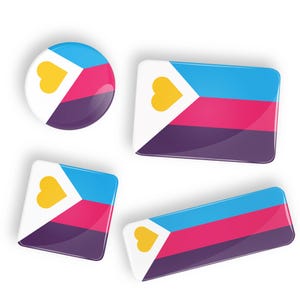 May include: Four different sizes of pins featuring a white background with a yellow heart, a blue triangle, a pink stripe, and a purple stripe.