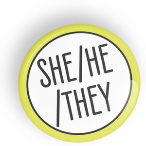 Pode incluir: Um botão amarelo com texto branco que diz "SHE/HE/THEY".