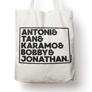 May include: White canvas tote bag with black text that reads "ANTONIS & TAN & KARAMOS & BOBBY & JONATHAN." The text is in a bold, sans-serif font and is enclosed in a black rectangle.