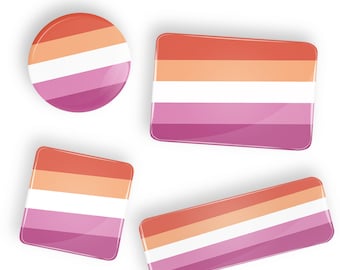 May include: Four lesbian pride flag pins in different sizes and shapes. The flag is pink, white, and orange.