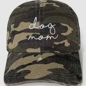 May include: A camouflage baseball cap with the words "dog mom" embroidered in white on the front.
