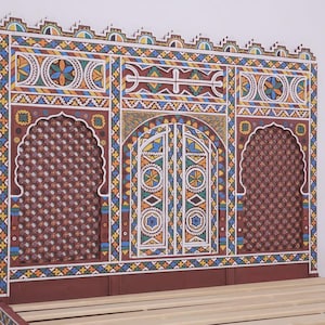 May include: A hand-painted headboard with a vibrant geometric design. The headboard features a central arched door design and two arched windows. The color scheme includes red, blue, yellow, and white. The bed frame is visible at the bottom.
