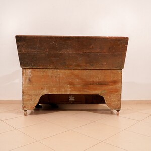 May include: A vintage wooden chest with a hinged lid and a carved design on the front. The chest is painted in a light brown colour and has a distressed finish.