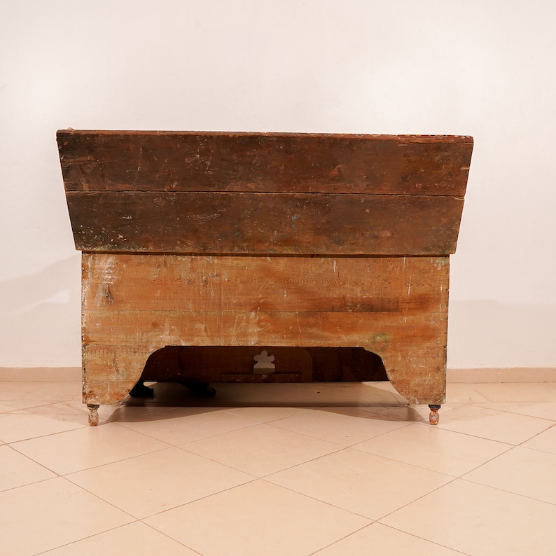 May include: A vintage wooden chest with a hinged lid and a carved design on the front. The chest is painted in a light brown colour and has a distressed finish.
