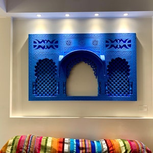 May include: A blue wall decor with intricate carvings in the shape of an archway. The decor is made of wood and has a traditional Moroccan design.