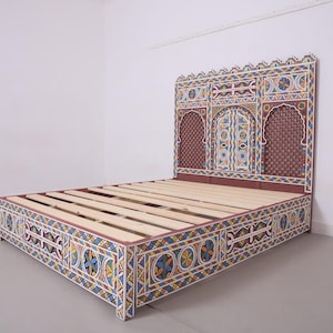 May include: A colourful bed frame with a headboard and footboard. The frame is painted with a geometric pattern in blue, yellow, red, and white. The headboard features an arched design with a patterned background.