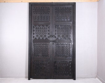 May include: A pair of dark brown wooden doors with intricate carved designs. The doors are made of solid wood and have a traditional Moroccan style.