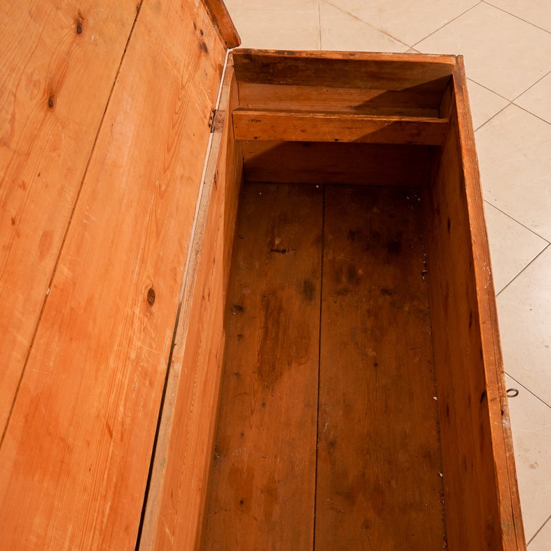 May include: An open wooden chest with a natural wood finish. The chest has a single shelf inside and is made of solid wood.