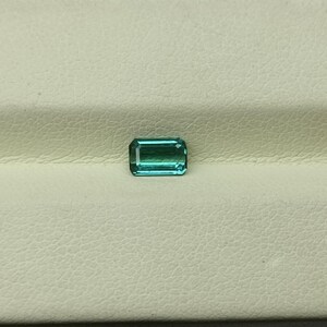 Op de afbeelding: Een rechthoekige, smaragd geslepen edelsteen met een lichtblauwgroene kleur.