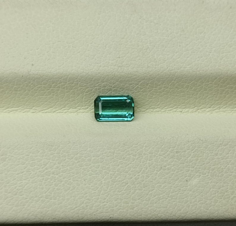 Op de afbeelding: Een rechthoekige, smaragd geslepen edelsteen met een lichtblauwgroene kleur.