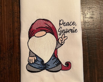 Paño de cocina de lino bordado con puntada de dobladillo. Bordado con gnomo hippie "Peace Gnomie"