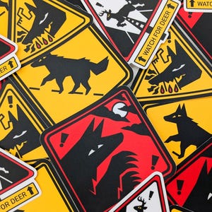 Peut inclure: Un ensemble d'autocollants d'avertissement jaunes, rouges et blancs. Les autocollants présentent des silhouettes noires de loups, de cerfs et de points d'exclamation. Certains autocollants portent l'inscription "WATCH FOR DEER".