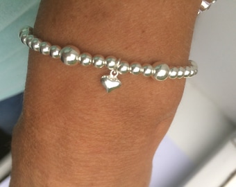 Pulseira em prata de lei com pingente de coração para usar em conjunto com outras pulseiras.