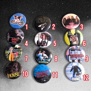 Peut inclure: Un ensemble de douze badges ronds sur le thème des films d'horreur. Les motifs incluent Gremlins, The Fly, The Lost Boys, Basket Case, Edward Scissorhands, The Return of the Living Dead, It, Re-Animator, The Shining, House, Fright Night et The Thing.
