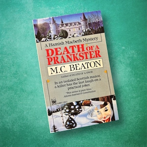 May include: A book cover with a snowy landscape and a castle in the background. The title is "Death of a Prankster" by M.C. Beaton. The book is part of the Hamish Macbeth Mystery series.