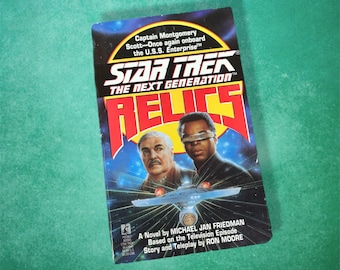 May include: A paperback book titled "Star Trek: The Next Generation: Relics." The cover shows two men and a spaceship against a blue and black space background. Text includes the author's name and episode details.