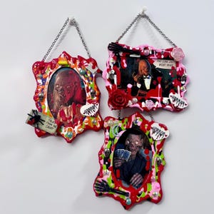 May include: Three decorative wall frames featuring horror-themed imagery, including a Tales from the Crypt character, a figure with the text The line just went dead, and a card player. The frames are adorned with red, green, and white paint drips.