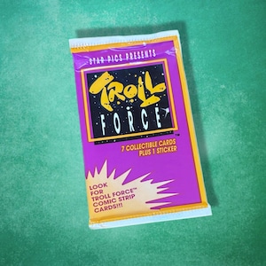 May include: A sealed pack of "Troll Force" collectible cards and a sticker. The package is purple with yellow and white text and graphics. The text includes "7 Collectible Cards Plus 1 Sticker" and "Look for Troll Force Comic Strip Cards!!!"