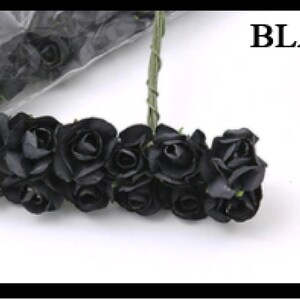 Puede incluir: Un ramo de peque&ntilde;as rosas de papel negro con tallos verdes. Las rosas est&aacute;n dispuestas en c&iacute;rculo y est&aacute;n atadas con una cinta verde. Las rosas est&aacute;n sobre un fondo blanco. BLACK est&aacute; escrito en texto negro sobre un fondo blanco.